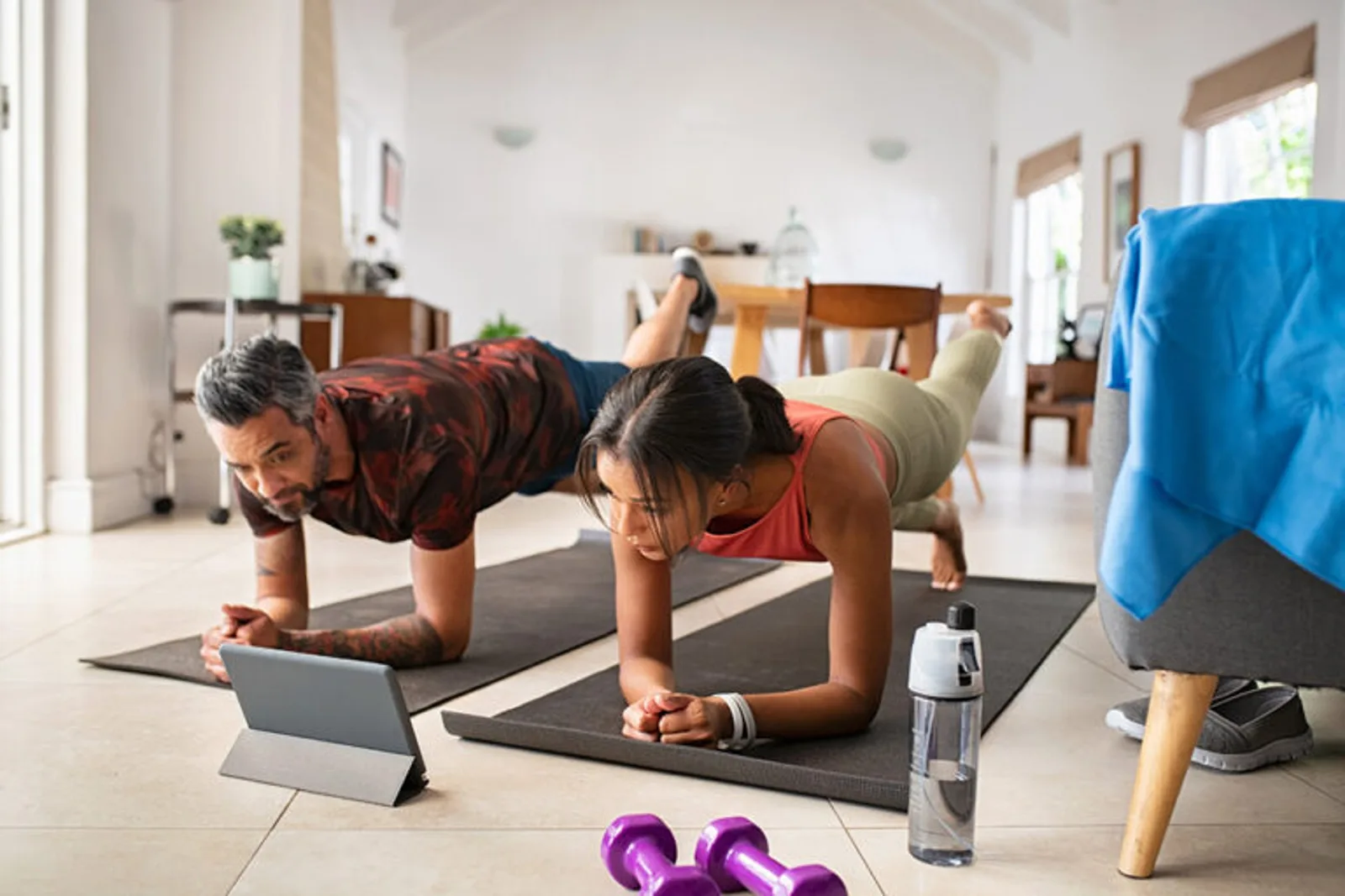 Zurück zur Kraft – Videokurs für Beweglichkeit von Till Sukopp 5 Paar macht Planks-Übung im Wohnzimmer auf Yogamatten mit Tablet und Hanteln