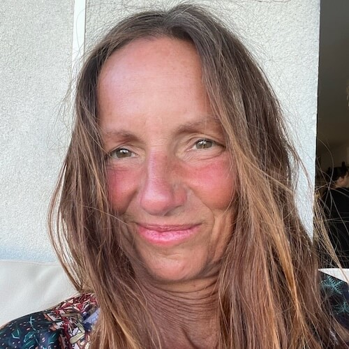 Porträt von Petra Kahanuola mit braunem Haar, lächelnd, beige Oberteil vor weißem Hintergrund
