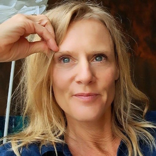 Porträt von Kerstin Halt mit blondem Haar und Hand an der Stirn