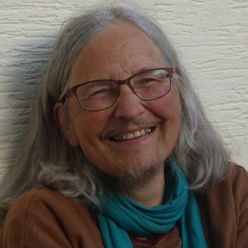 Porträt von Eva Fellerer mit grauem Haar und Brille, vor weißem Hintergrund