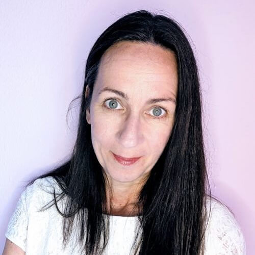 Porträt von Dr. Ilona Schönwald mit schwarzem Haar vor rosa-violettem Hintergrund