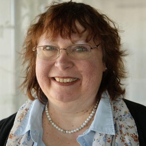 Porträt von Monika Müller-Herrmann mit braunem lockigem Haar und Brille