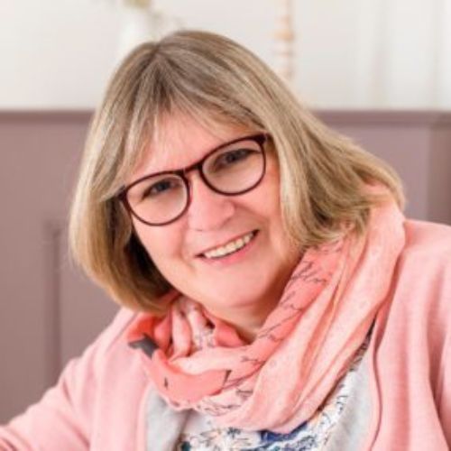 Porträt von Edith Sauerbier, Frau mit blondem Bob-Haarschnitt, Brille und rosa Schal